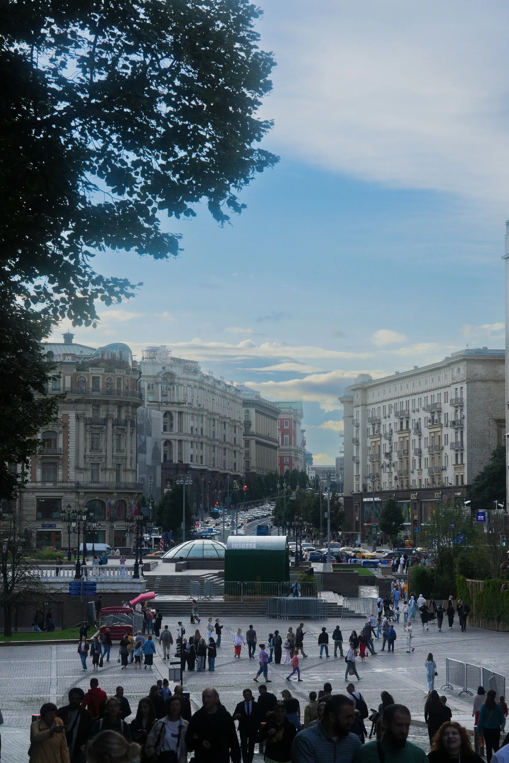 Moscow in August. Old facades, a busy square, and a tree framing the top.