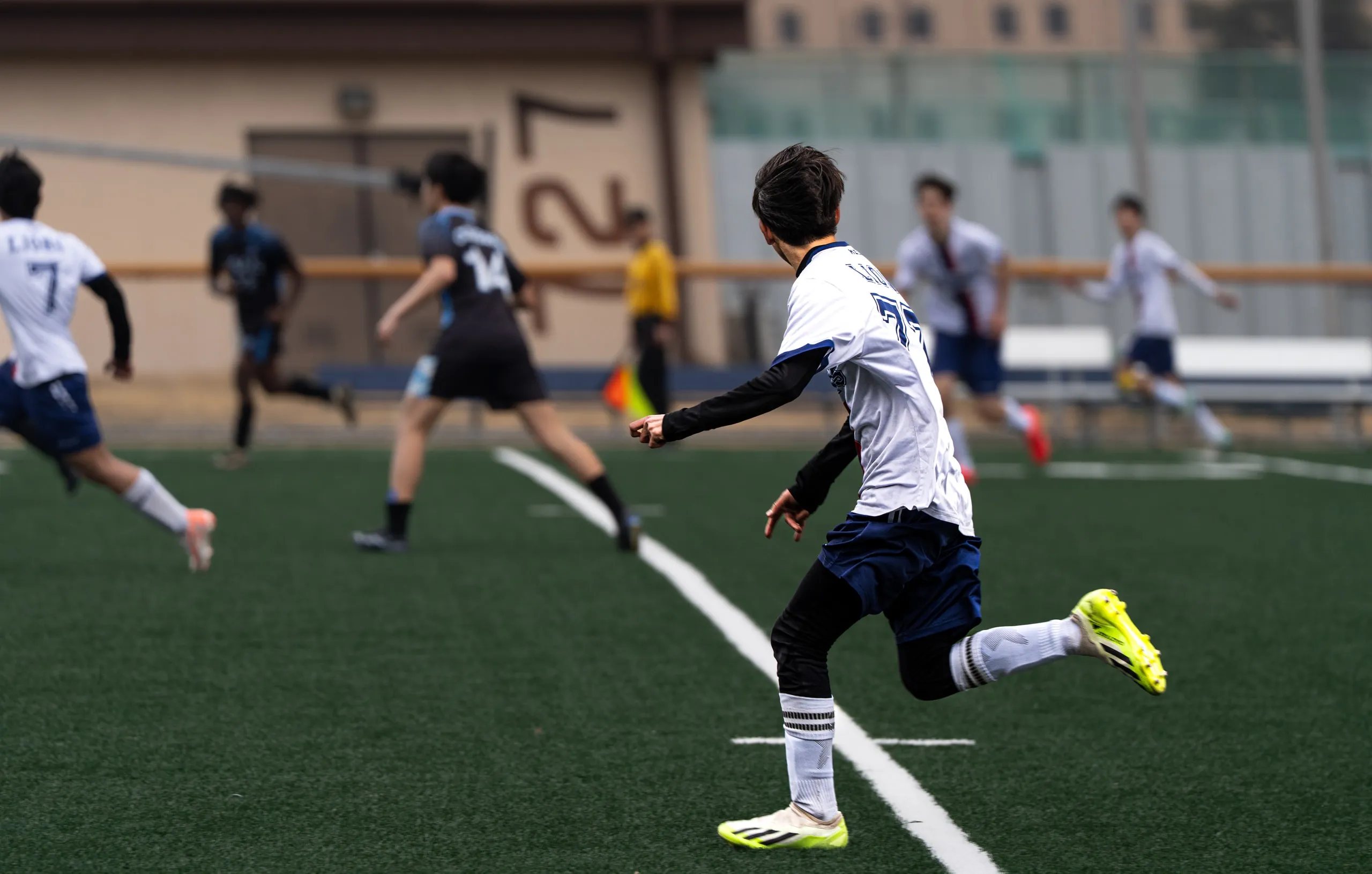 Mid stride on the pitch. Neon boots, eyes on the play.
