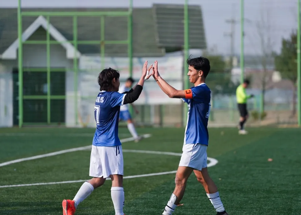 A high five between teammates. The captain's armband on the right.