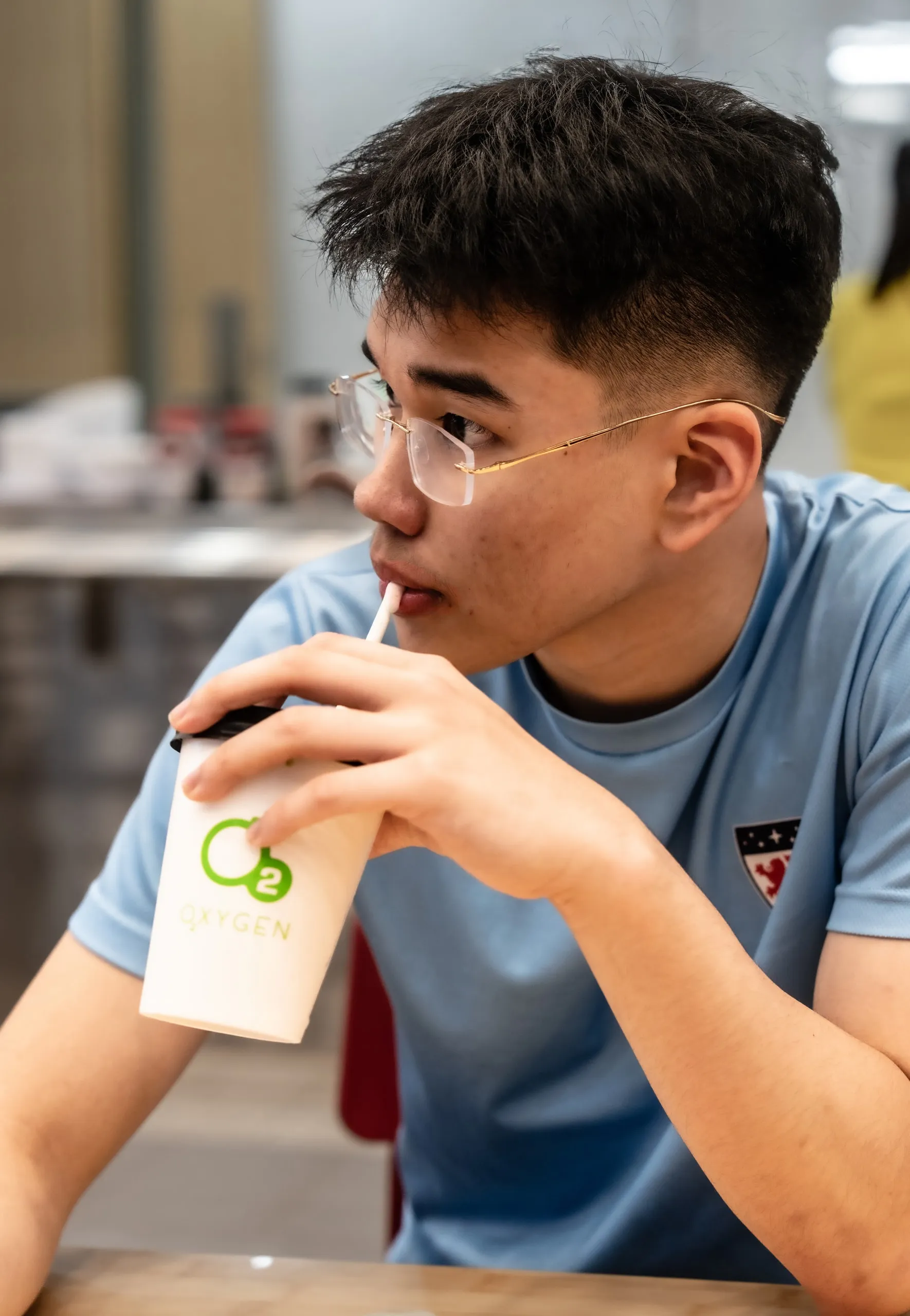 Mid sip. Glasses on, iced drink in hand.