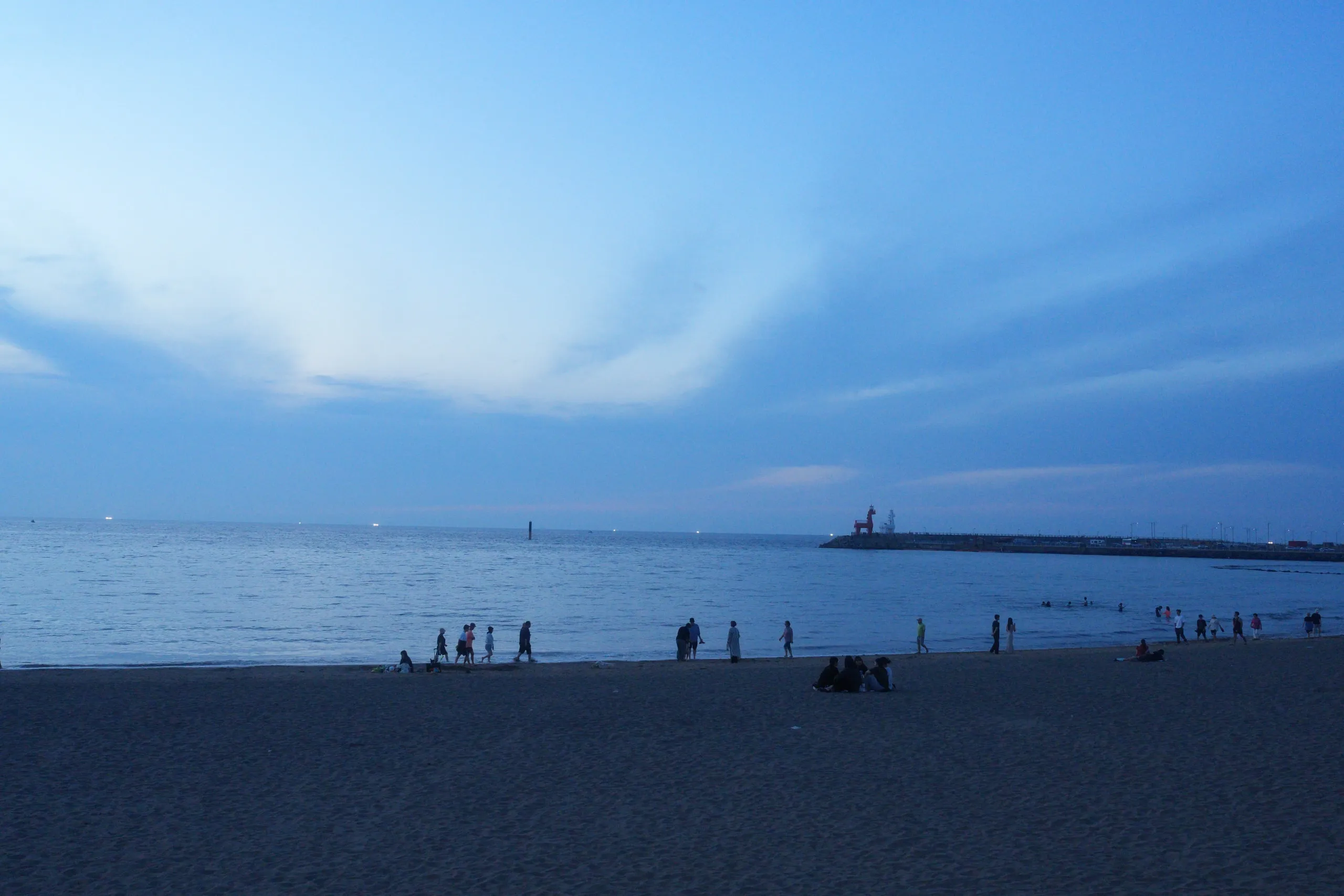 Blue hour on a Jeju beach. People walking the shoreline.