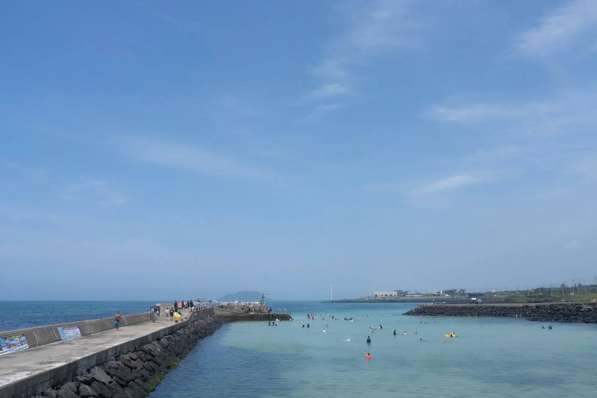The same breakwater from the other side. Swimmers in the clear water.
