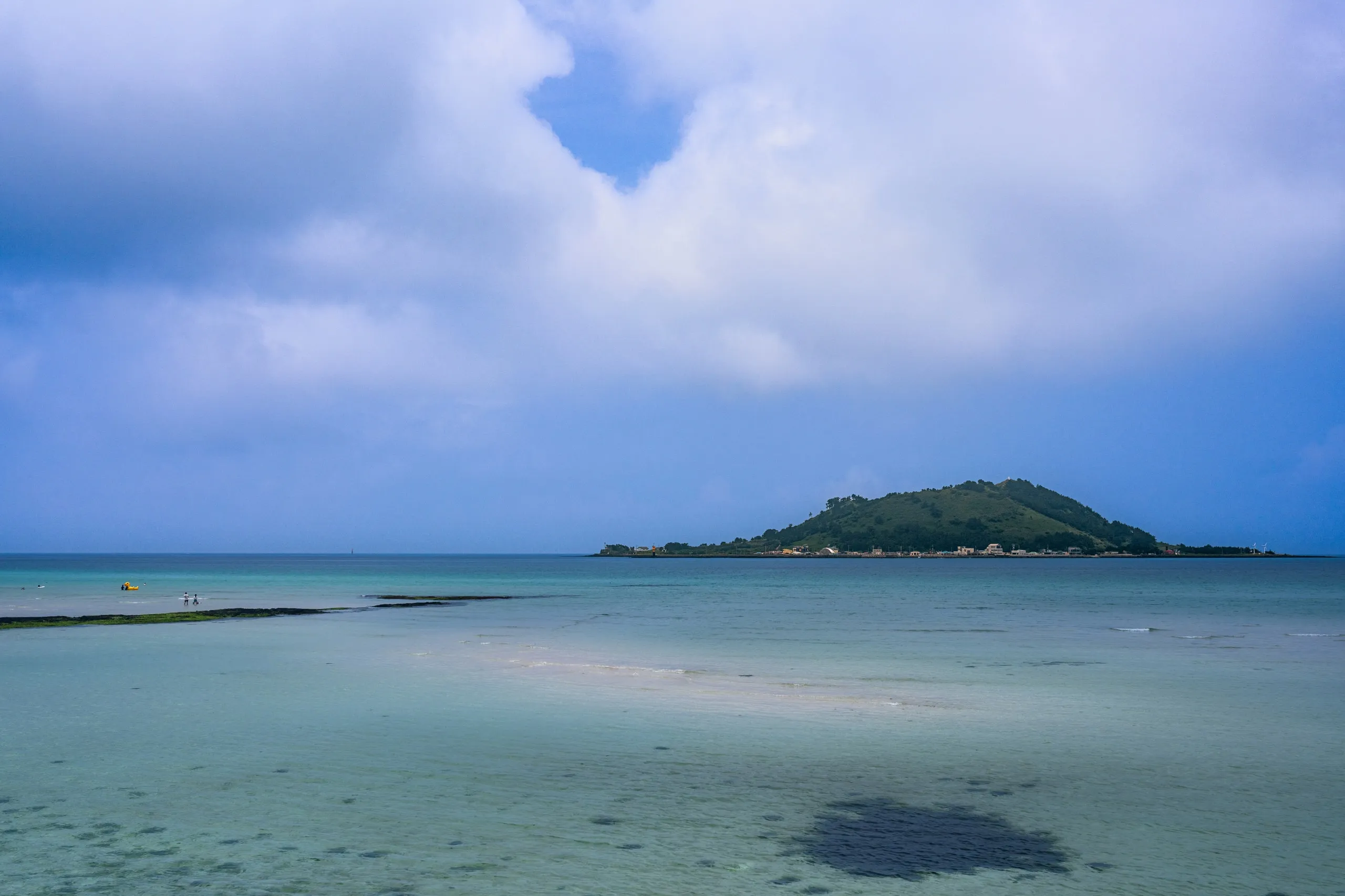 Jeju. Shallow clear water and a small island offshore.