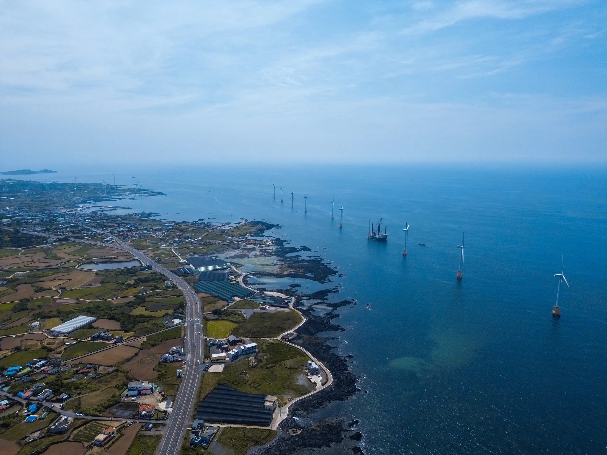 Jeju from the drone. Wind turbines standing out in the sea.