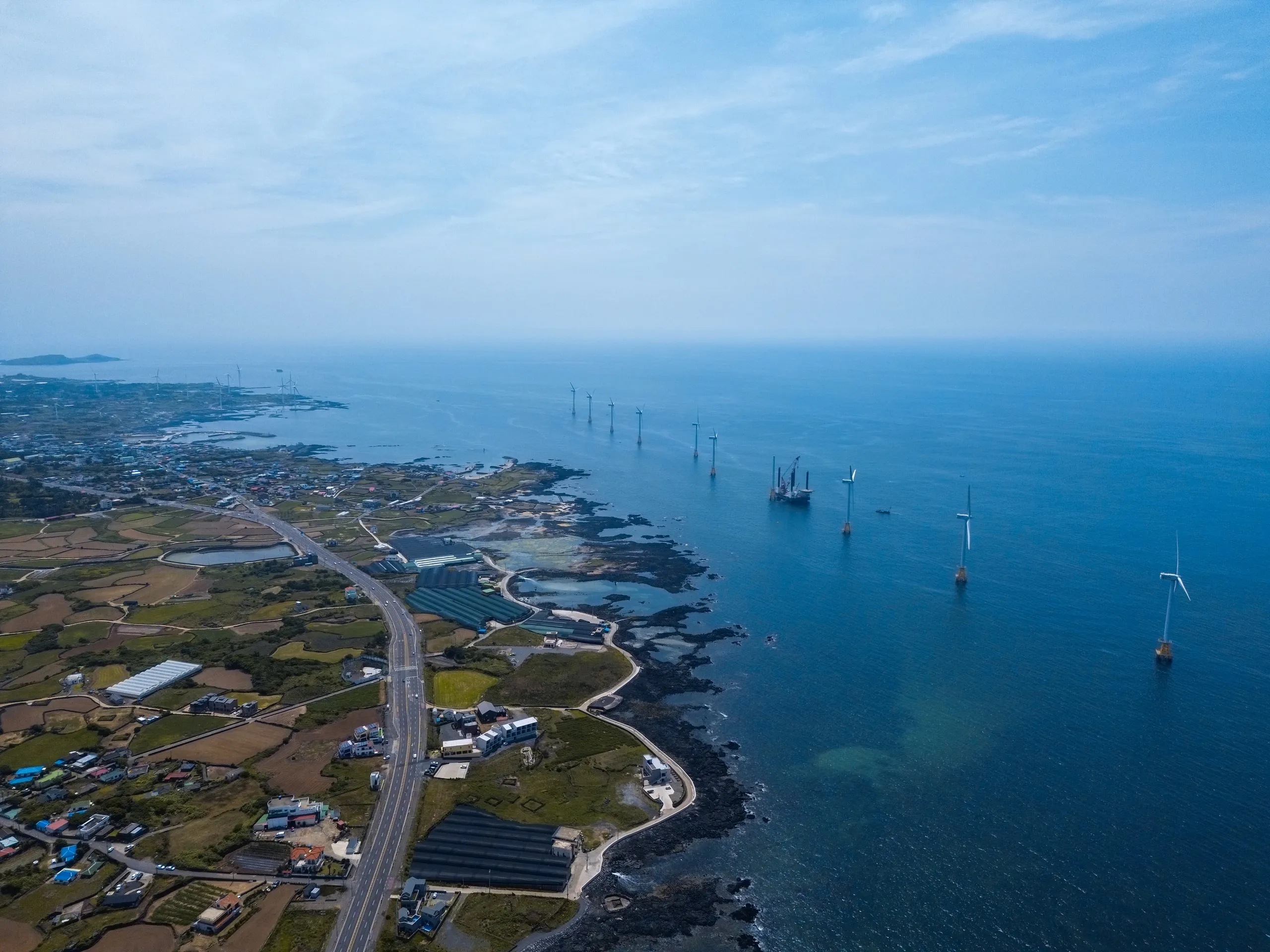 Jeju from the drone. Wind turbines standing out in the sea.
