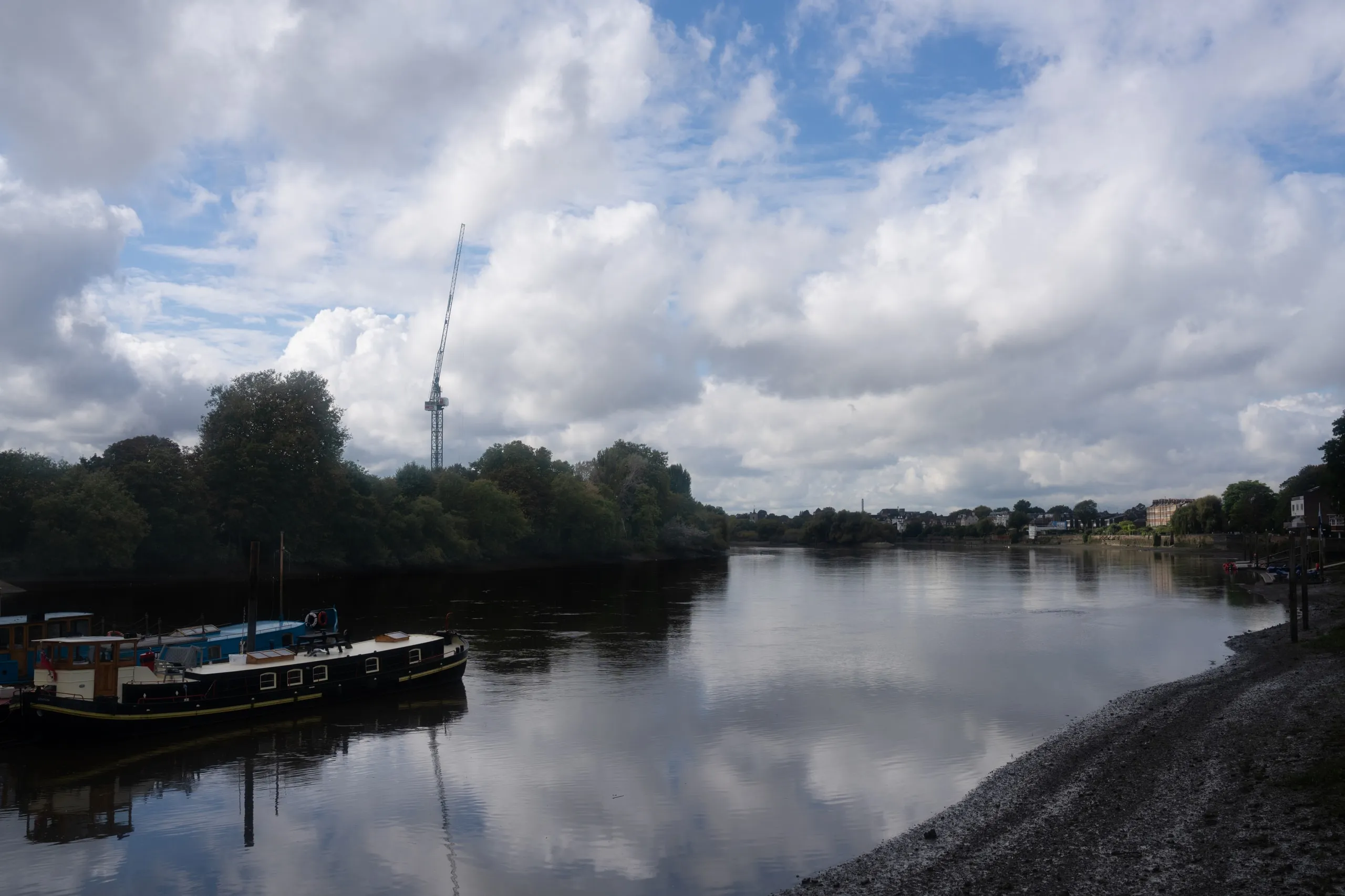 London, by the river. Boats tied up under a big cloudy sky.